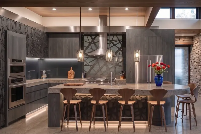 Dark wood kitchen with laser-cut branch-pattern panels, concrete island, woven pendant lights and walnut bar stools