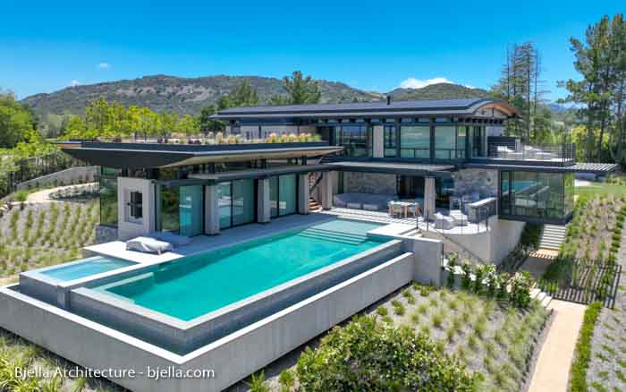 Modern stone and glass hillside house with pool, aerial view