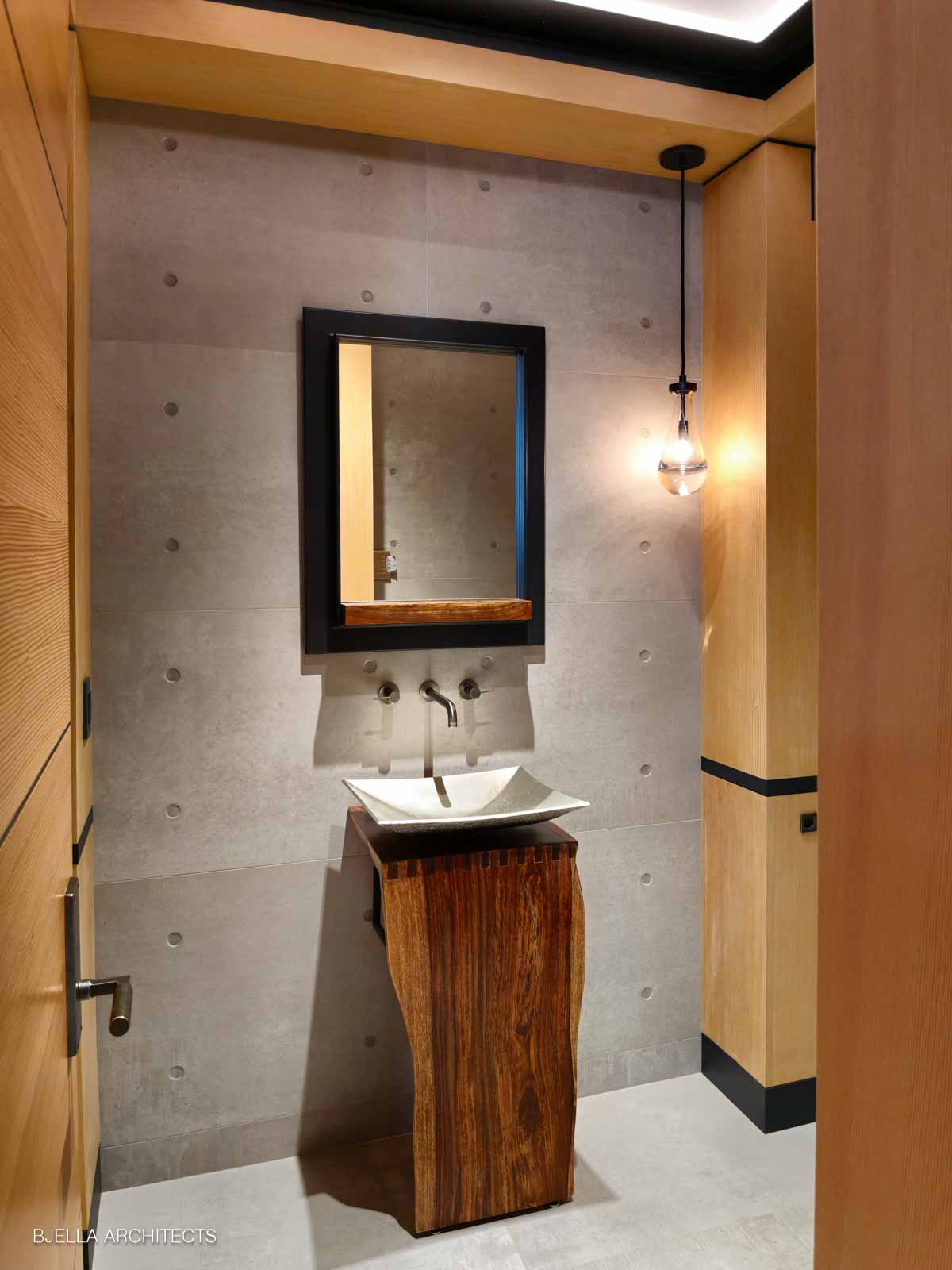 Sculptural walnut pedestal sink against board-formed concrete