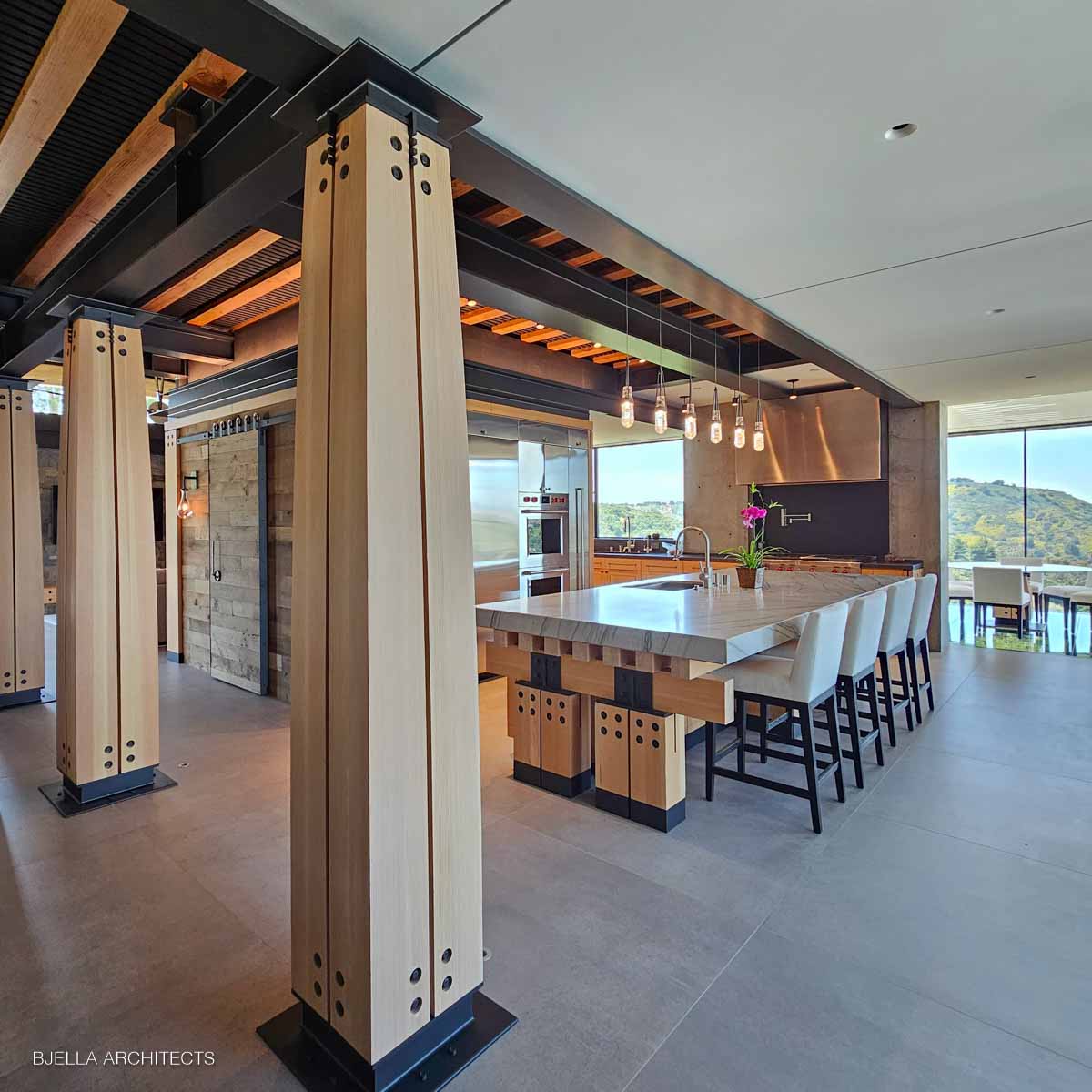 The kitchen beneath its beamed ceiling, timber columns framing the view