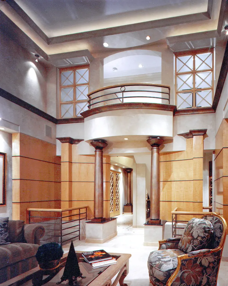 Curved balcony on two dark columns after remodeling, between cross-pane windows above wood-paneled walls