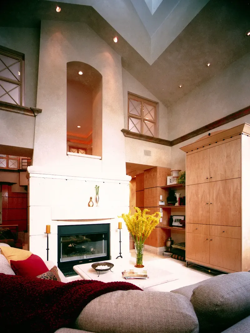 Room with a white fireplace below an arched opening, vaulted ceiling with skylight, and a tall wood armoire