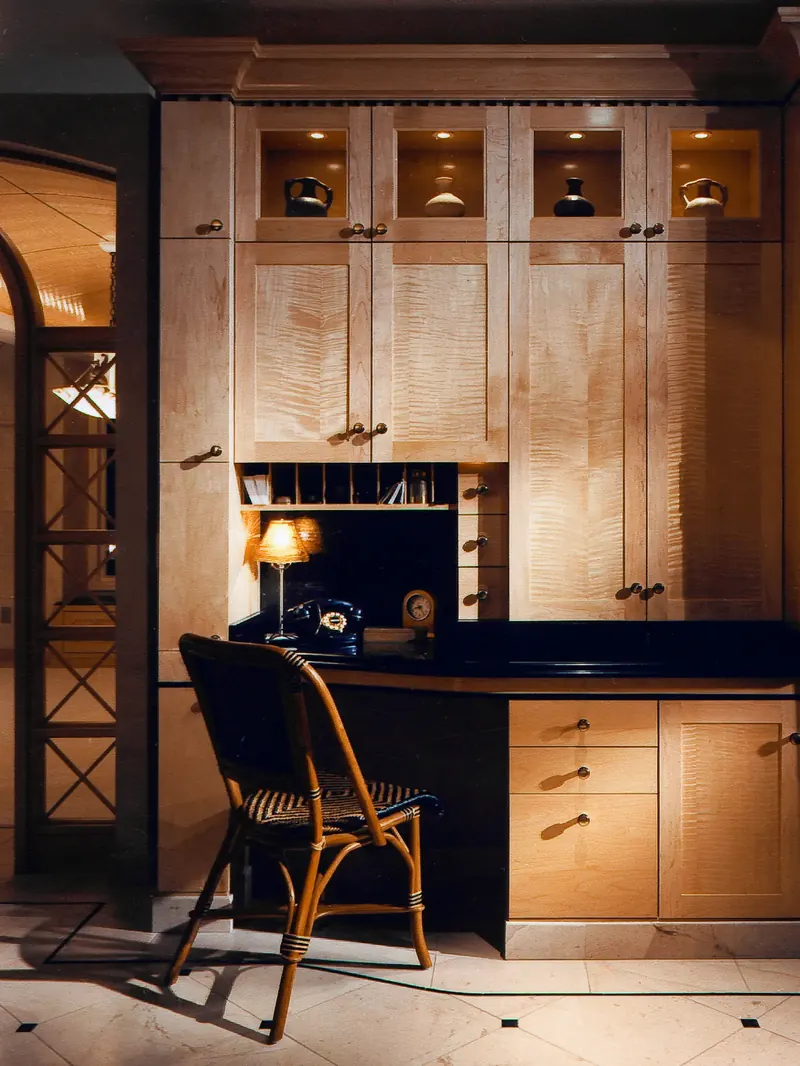 Kitchen desk after remodeling: built-in wood cabinetry with lit display cubbies, mail slots and a rattan chair