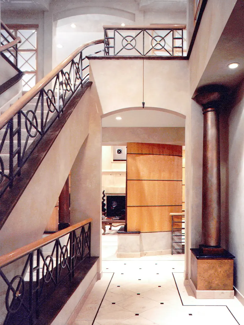 Stairway after remodeling: iron balustrade with circle motifs, arched opening, dark column and inlaid tile floor