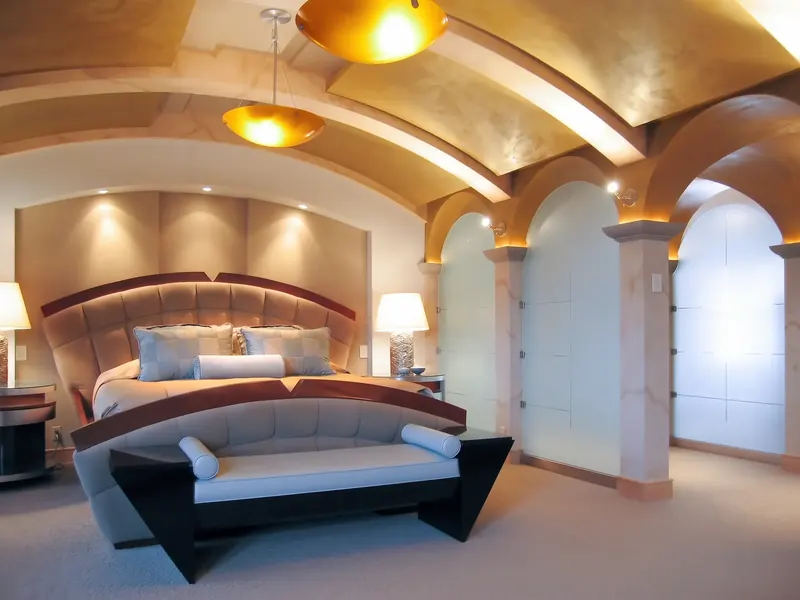 Primary suite with a curved ceiling, an upholstered bed and frosted glass partitions