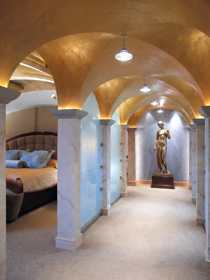 Vaulted gold-toned hallway lined with columns leading to a bronze sculpture