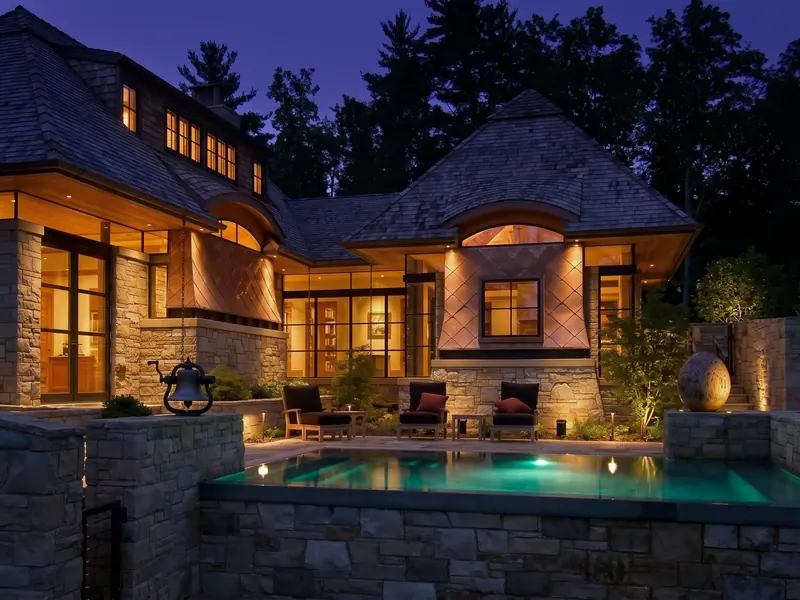 The copper-clad home and stone terraces glowing at dusk above the pool