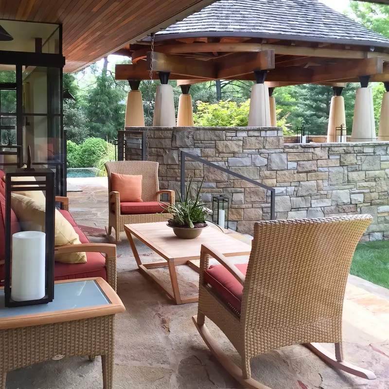 Covered lounge with wicker rocking chairs and a wood coffee table, looking toward the columned dining pavilion