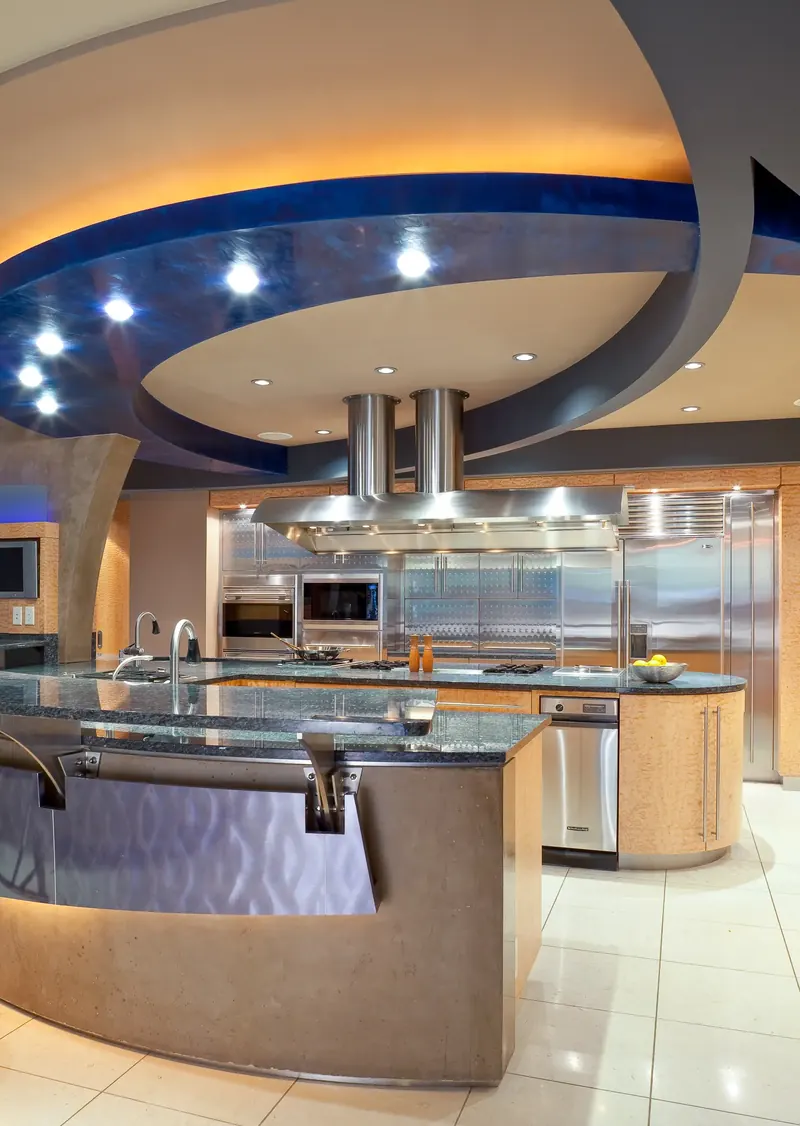Curving blue and cream ceiling bands over the kitchen island, twin-flue stainless hood and stainless wall
