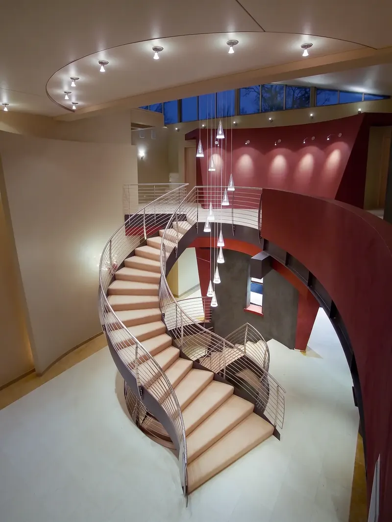 View down from above onto the S-curved staircase at dusk, pendants hanging through the open stairwell
