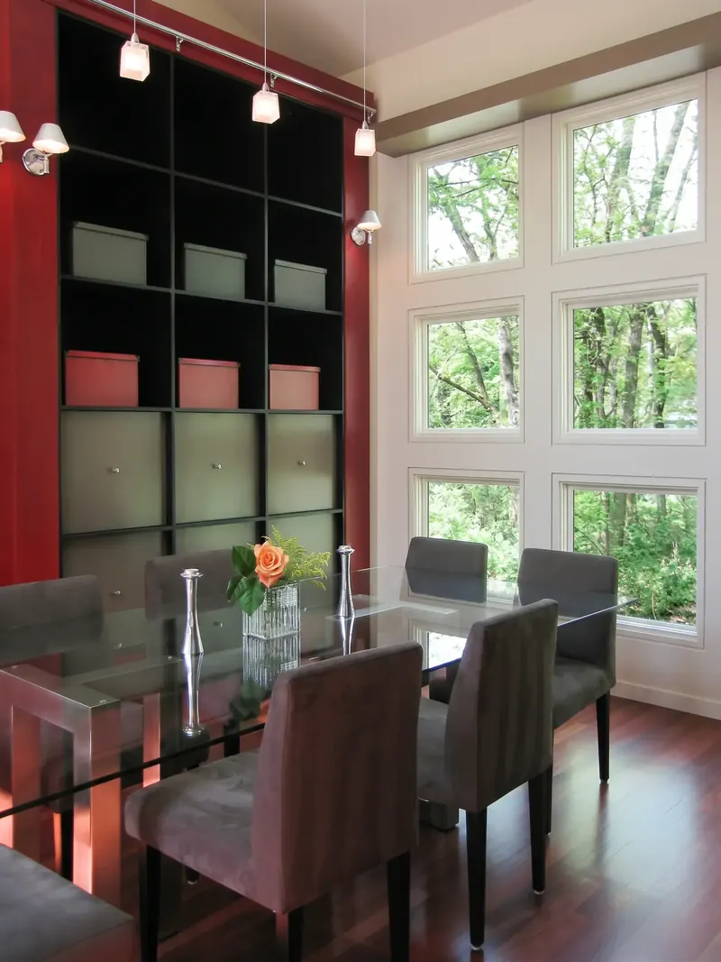 Dining room with a glass table, black grid shelving and a wall of windows