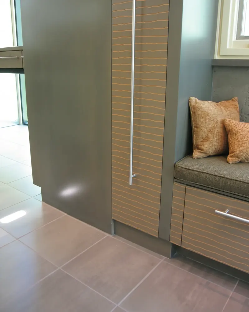 Window bench beside a grey cabinet tower with slatted wood fronts
