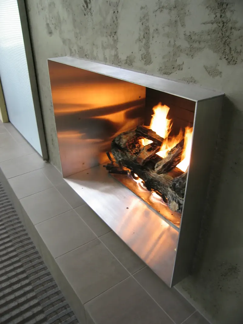 Custom stainless steel fireplace set into a textured plaster wall