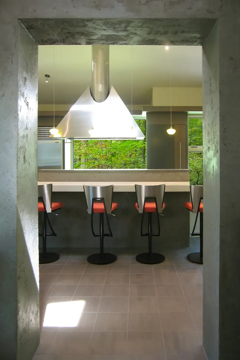 View through a plaster portal to the bar seating and the stainless steel hood