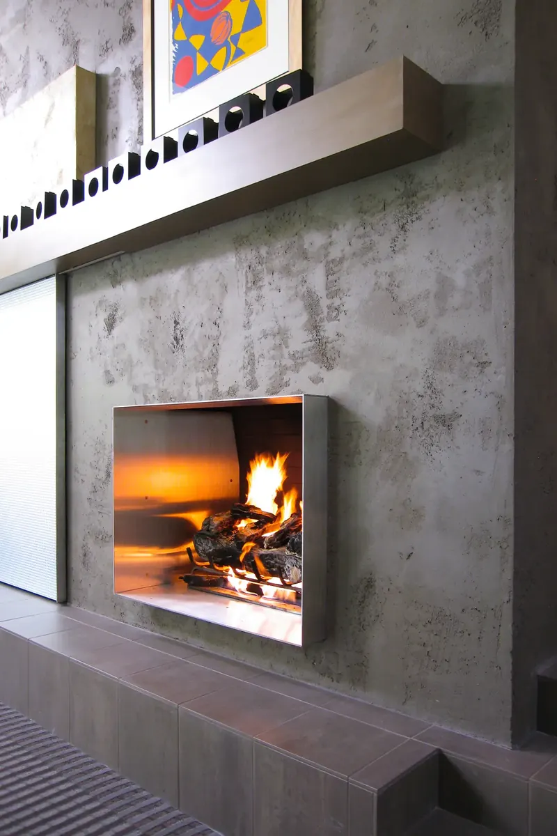 Stainless steel fireplace beneath a long floating shelf