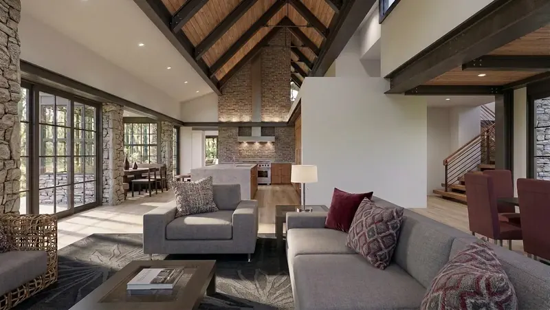 Living area under a vaulted wood ceiling with dark steel trusses, looking toward the kitchen's tall brick wall