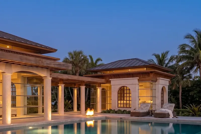 Pavilion colonnade and an adjoining stone building with arched windows across the pool