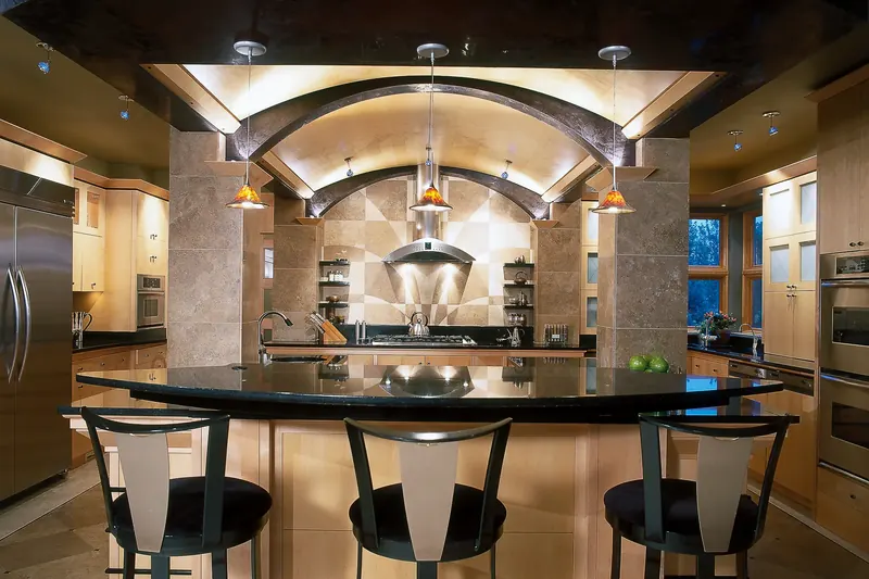 Kitchen with a curved black countertop bar, an arched ceiling and stone columns