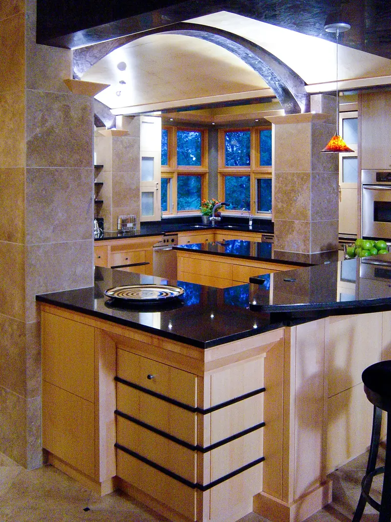 Corner of the kitchen island with black-banded maple drawers and a dark countertop