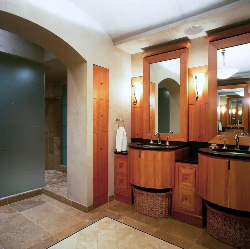 En-suite bath with dual curved wood vanities and tall framed mirrors