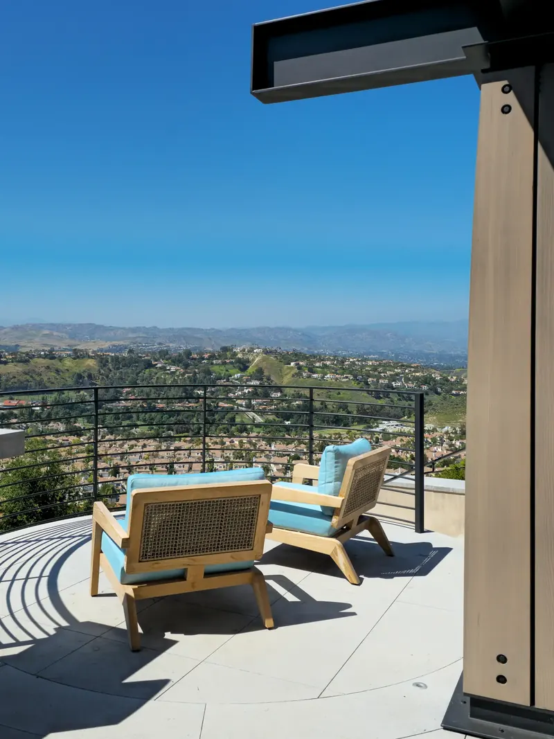 Two wood lounge chairs on the circular overlook deck facing the valley and distant mountains