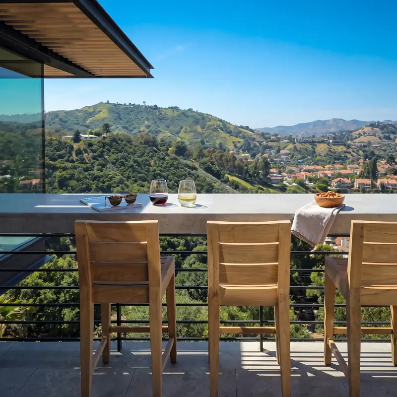 Concrete high bar with wood stools at the deck rail, looking across the green valley
