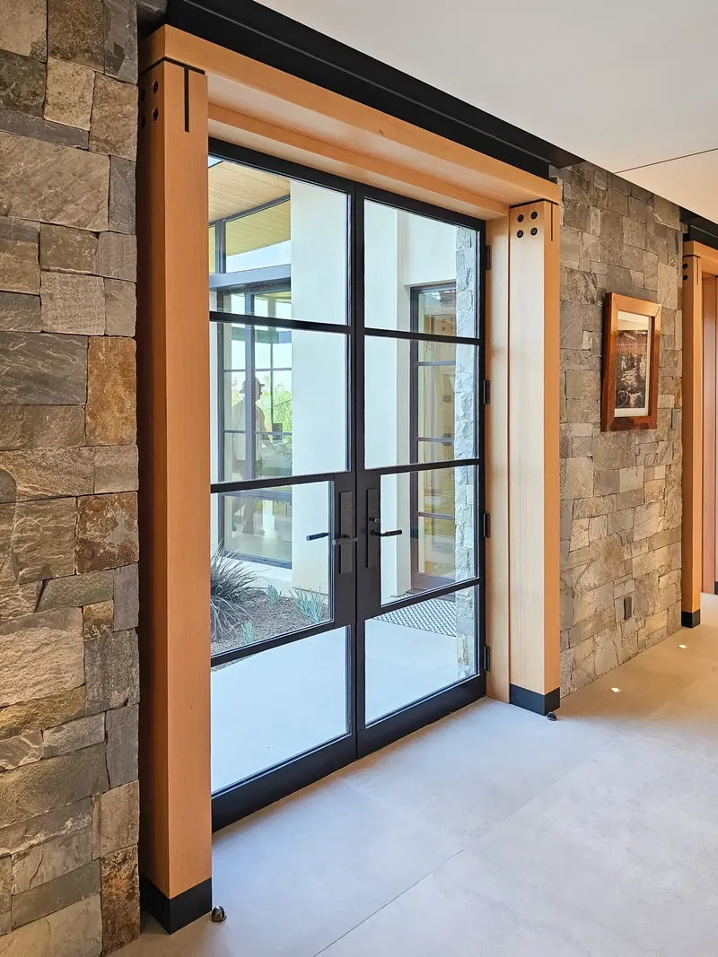 Steel-framed glass double doors in a bolted timber surround set into a stone wall