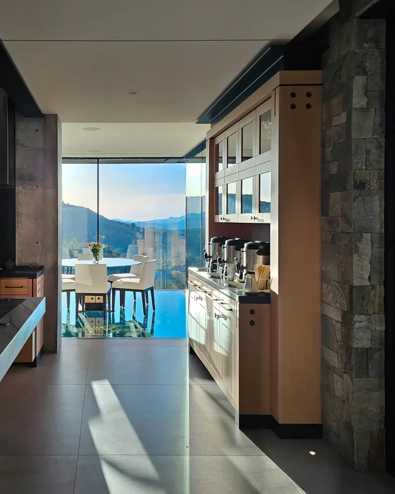 Fir display cabinetry beside a stone wall, leading the eye to the glass dining room and mountains