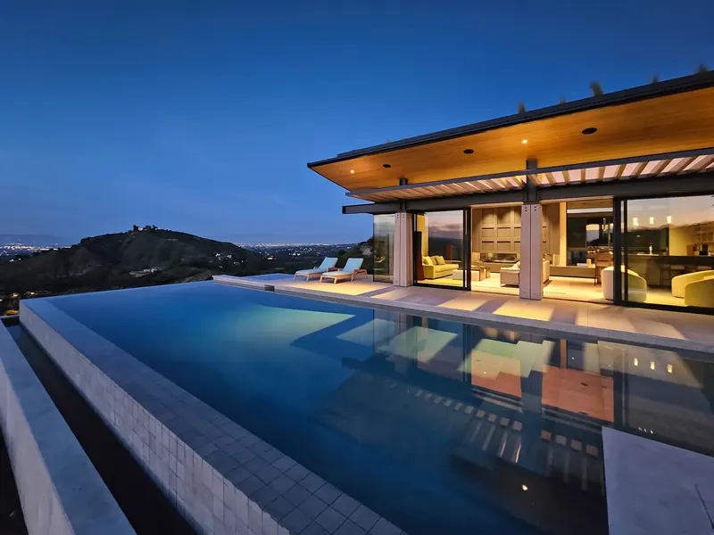 Infinity pool at blue hour, the View Room glowing beneath its wood soffit and city lights below