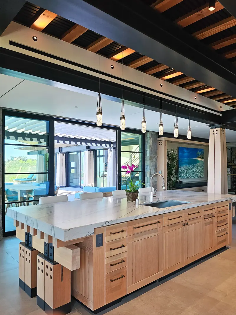 Douglas fir center island with stone top and pendant lights, steel-framed glass doors to the terrace