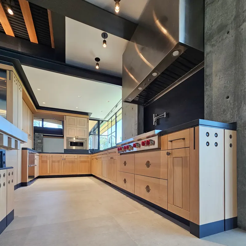 Cooking wall with a stainless hood set against exposed concrete above Douglas fir cabinetry