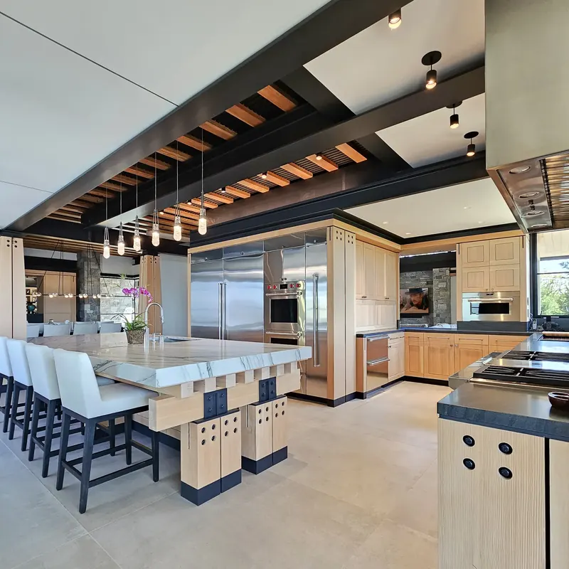 Kitchen seen from the dinette: island seating, steel beams and a tall wall of appliances and fir cabinetry