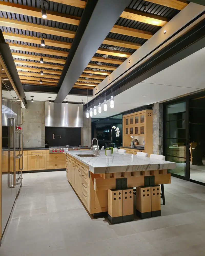 Kitchen with a stone-topped timber island beneath a beamed ceiling and a row of pendants