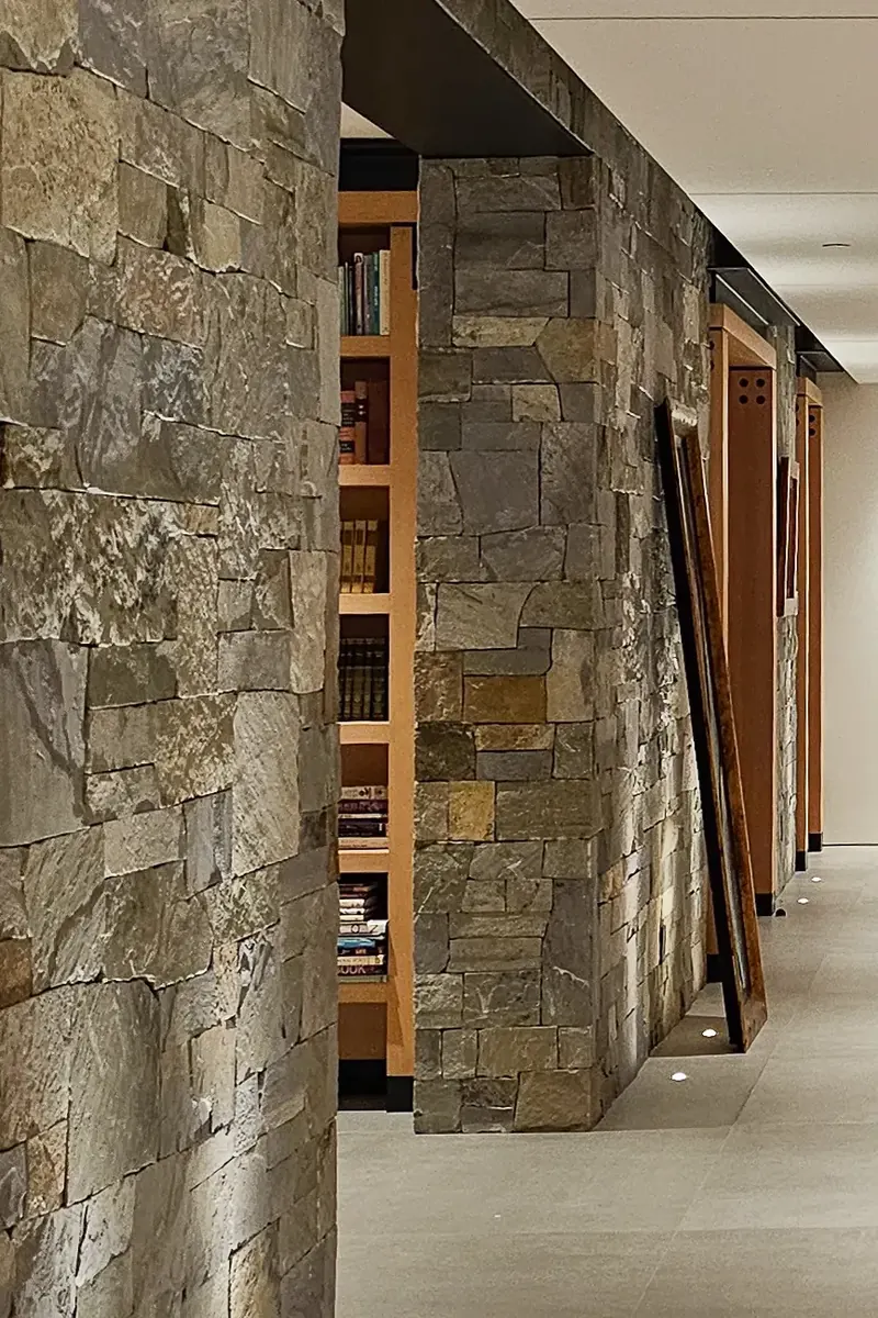 Thick stone wall with a deep opening revealing library shelves along a hallway