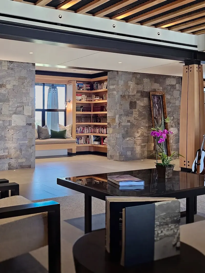 Library window seat and corner bookshelves framed by thick stone walls and a timber column