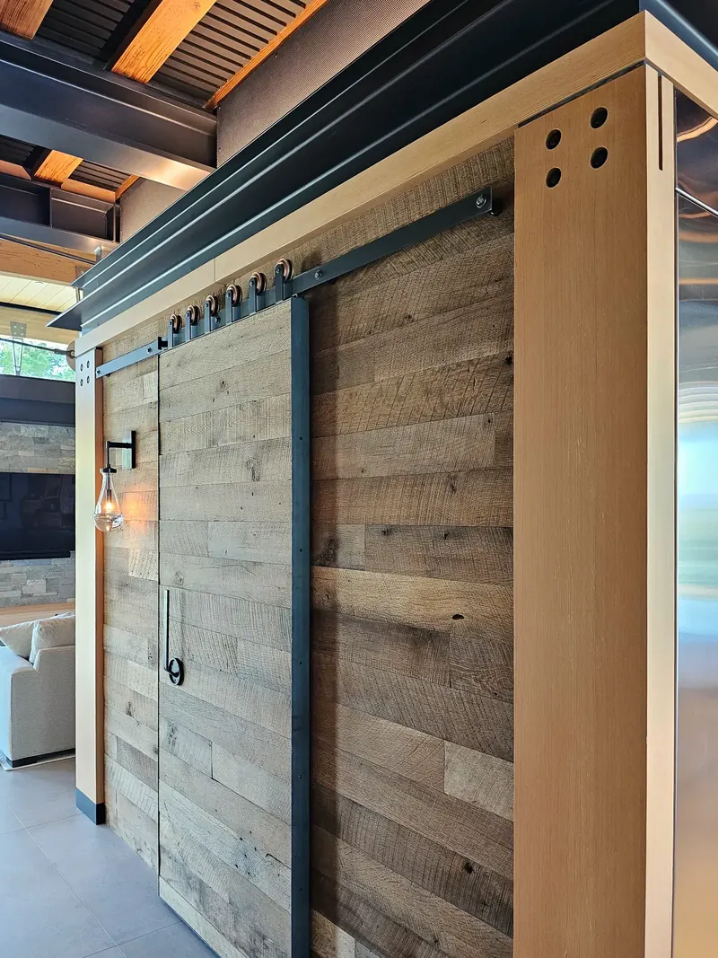 Walk-in pantry clad in reclaimed lumber, with a matching sliding barn door on copper wheels