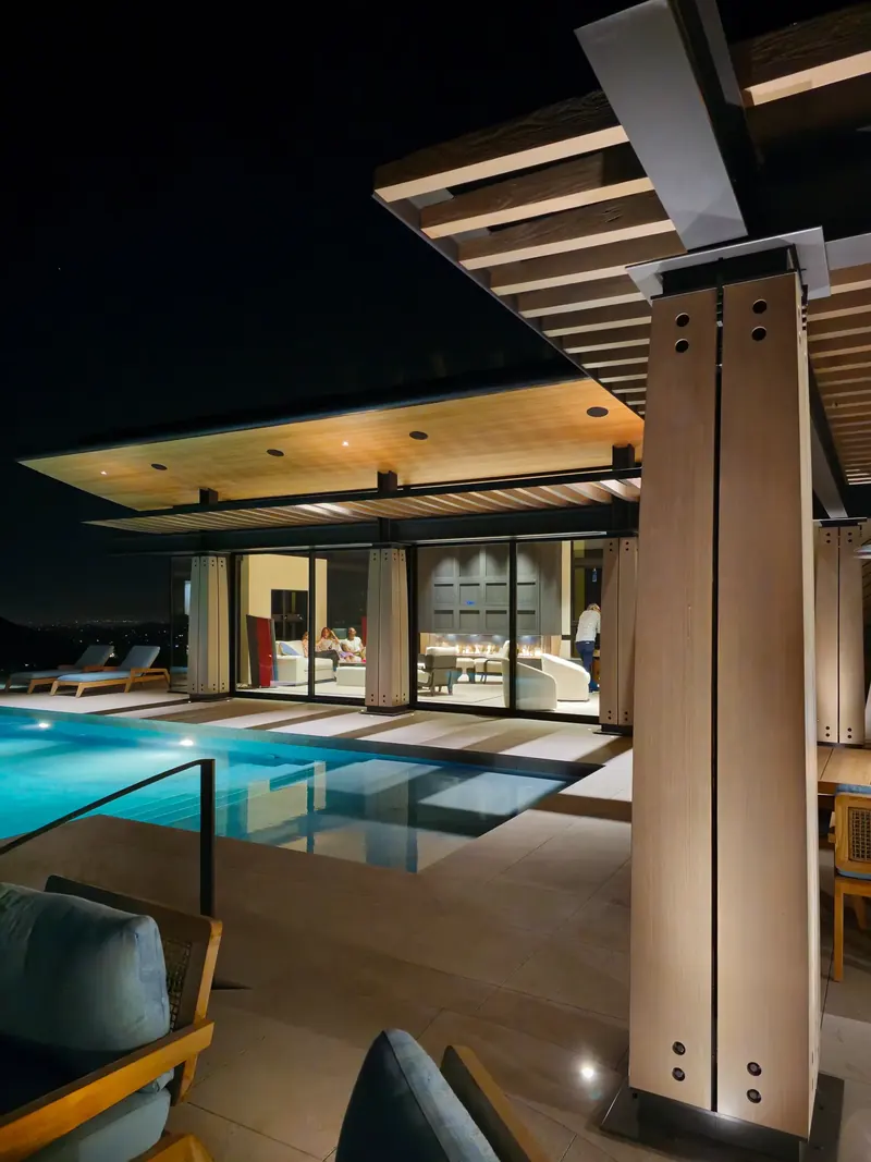 Timber column and trellis at night, the lit pool and View Room beyond