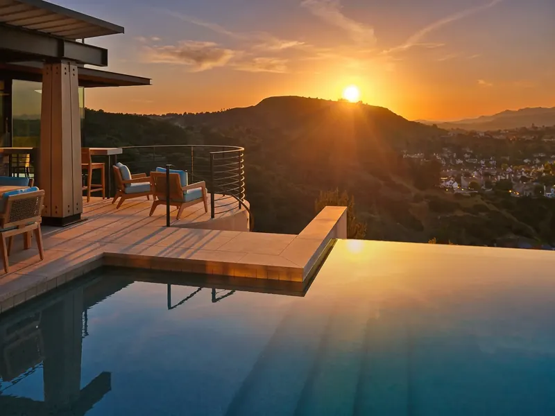 Sun setting over the hills, reflected in the infinity pool beside the circular seating deck