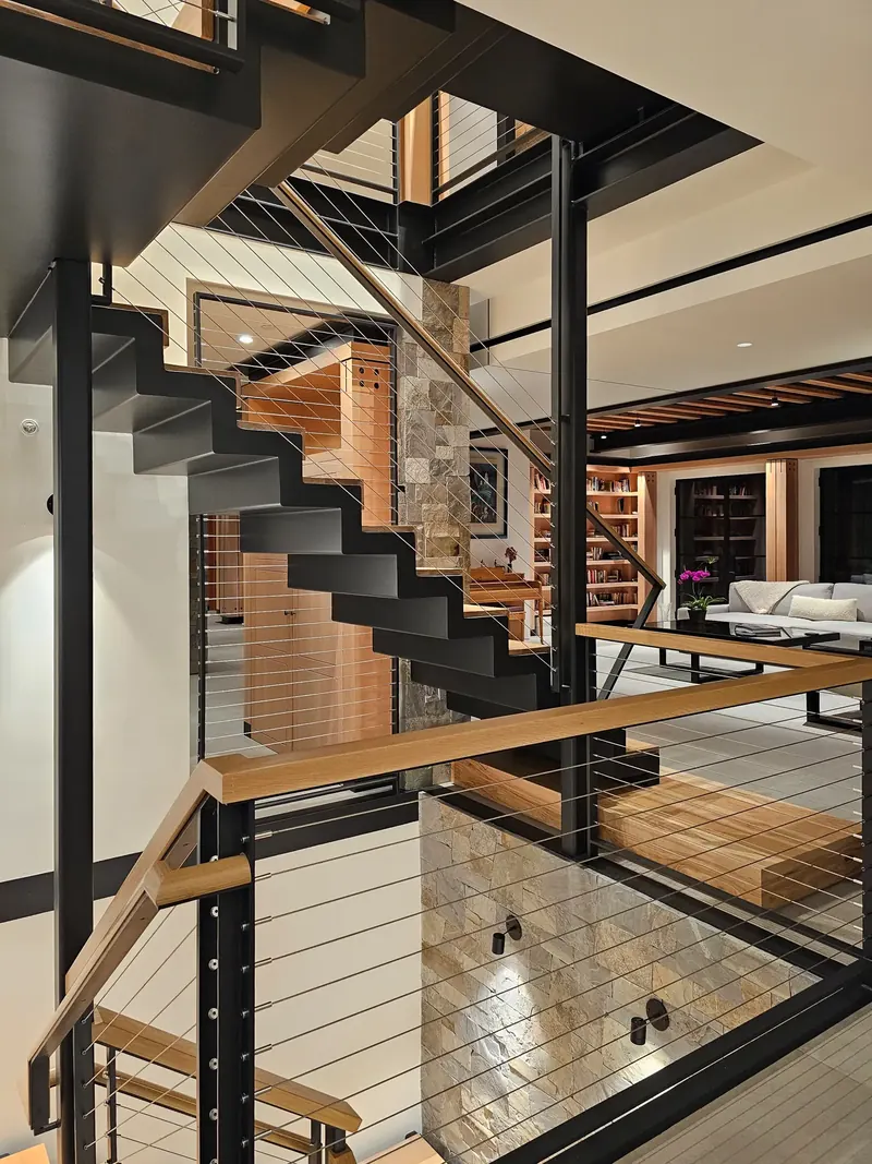 Steel and wood staircase with cable railings rising through the house