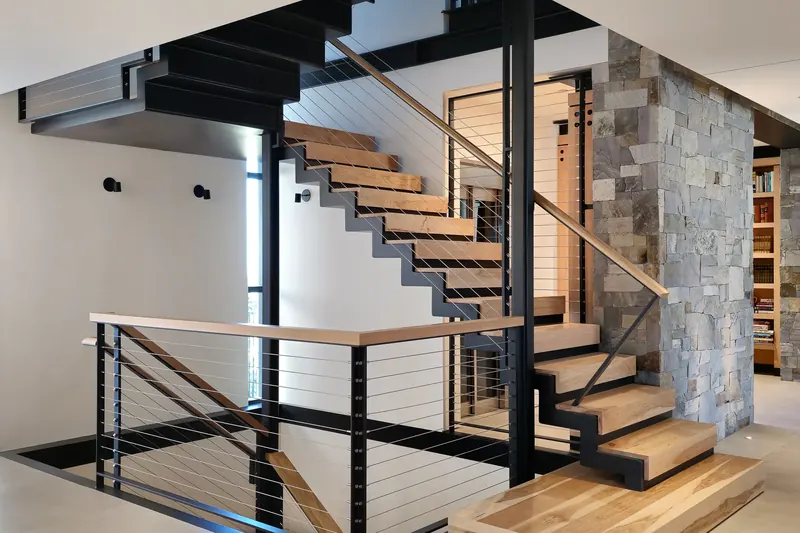 Floating steel and timber stair beside a stone wall