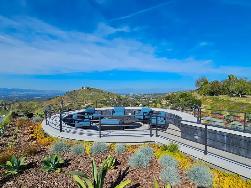Sunken circular roof deck ringed by a steel rail and planted roof, a lone hill and valley beyond