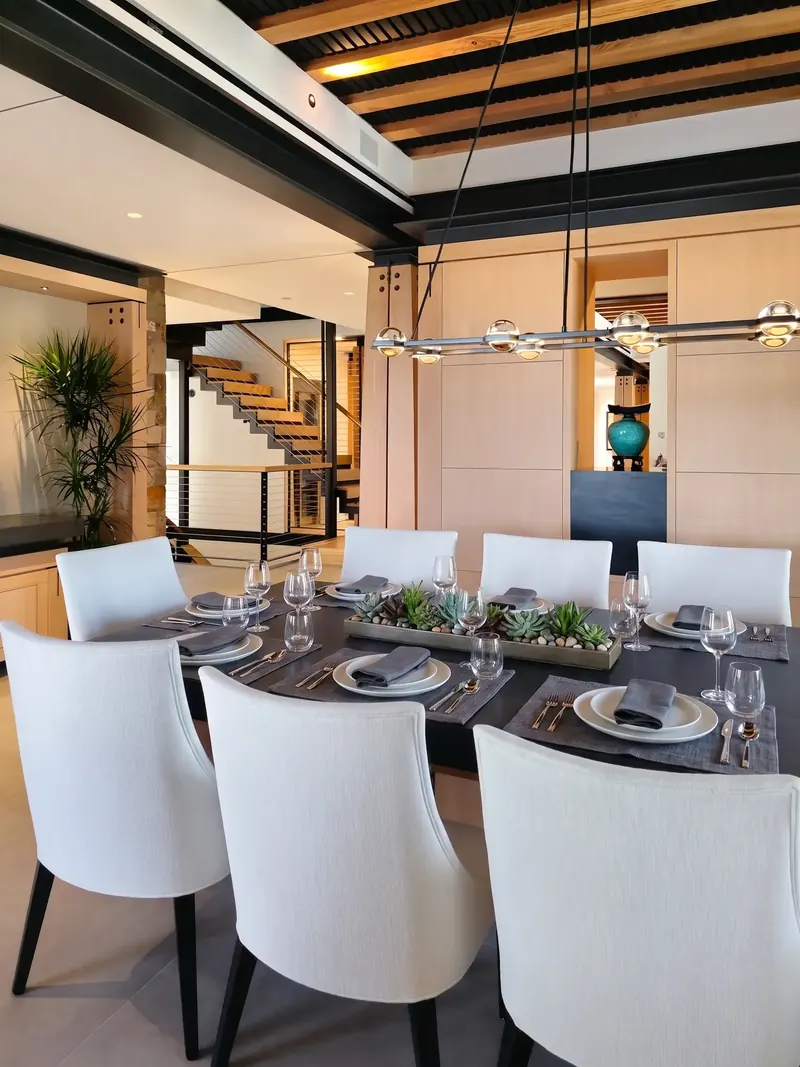 Set dining table with an open-riser staircase and built-in wood cabinetry in the background