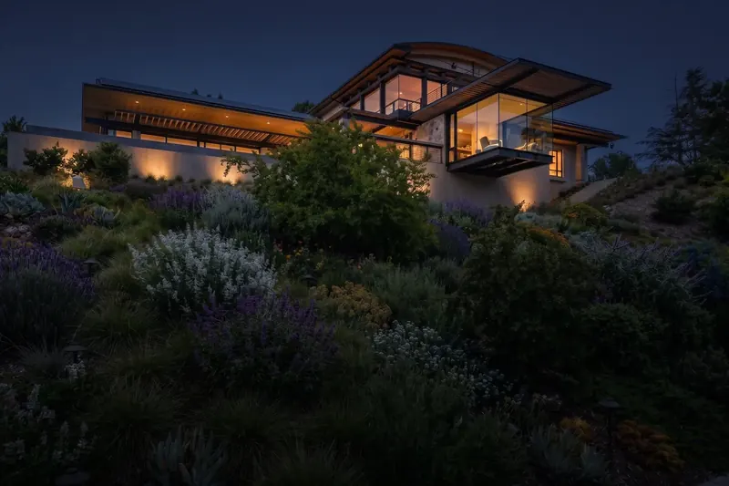 The house seen at dusk from the planted hillside below