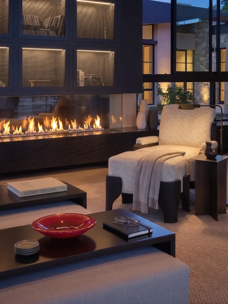 Linear fireplace and a lounge chair in the View Room at dusk