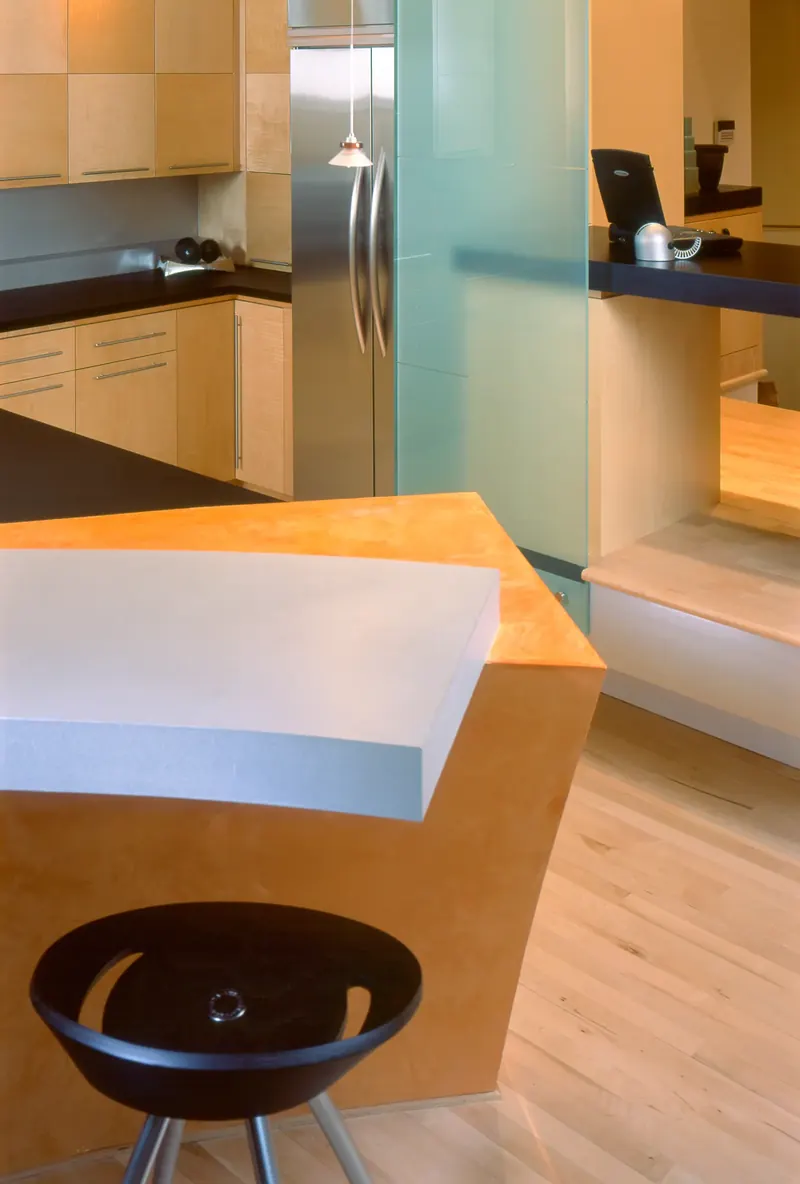 Close-up of the curved orange breakfast bar and its floating metallic countertop