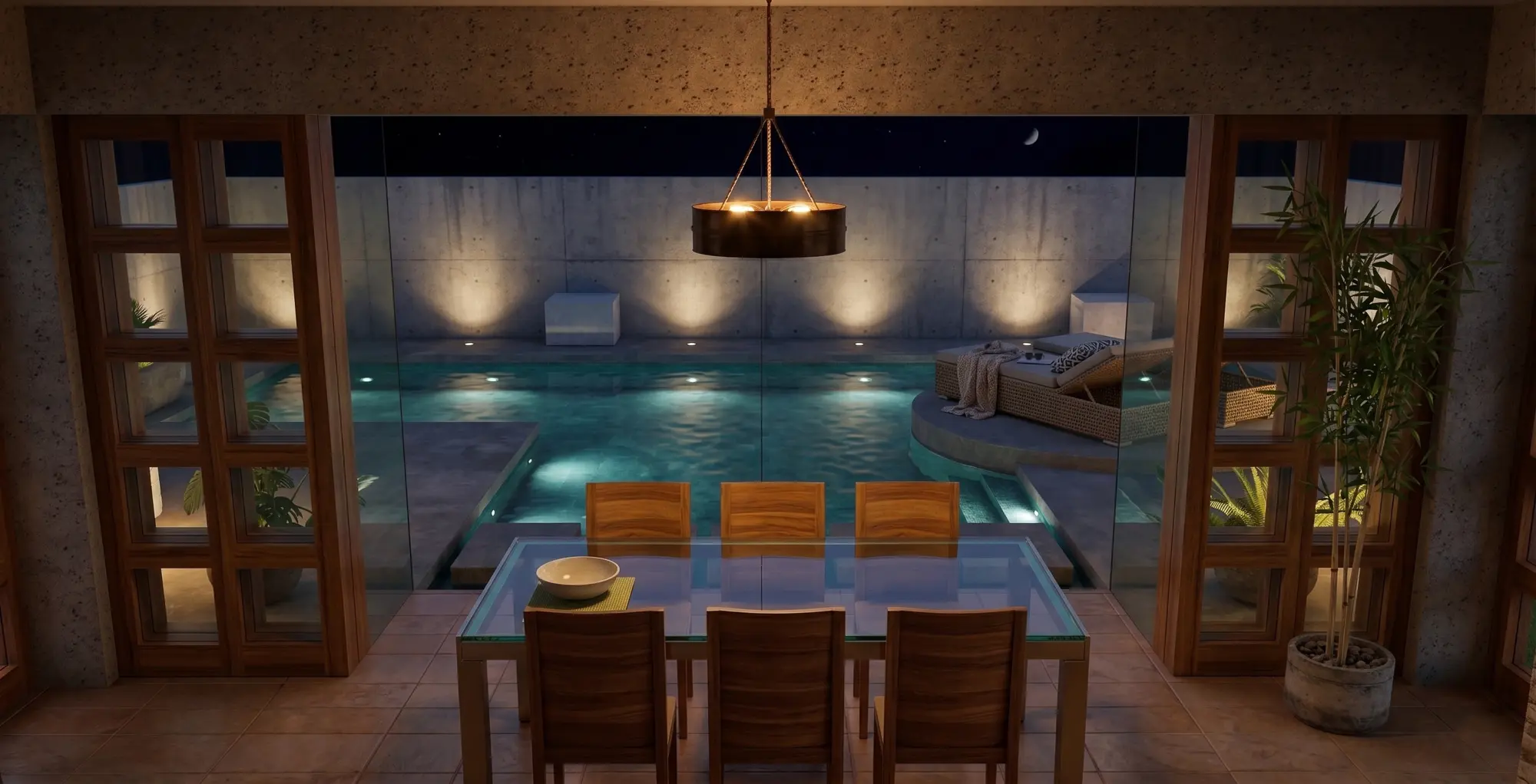 Dining room at night looking through glass walls to a lit pool, sun lounge and concrete garden wall