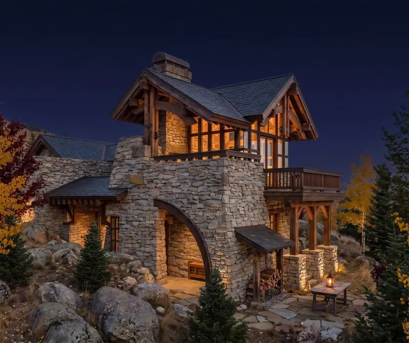 Stone Tower House at night, the timber-framed tower room glowing above the arched stone base