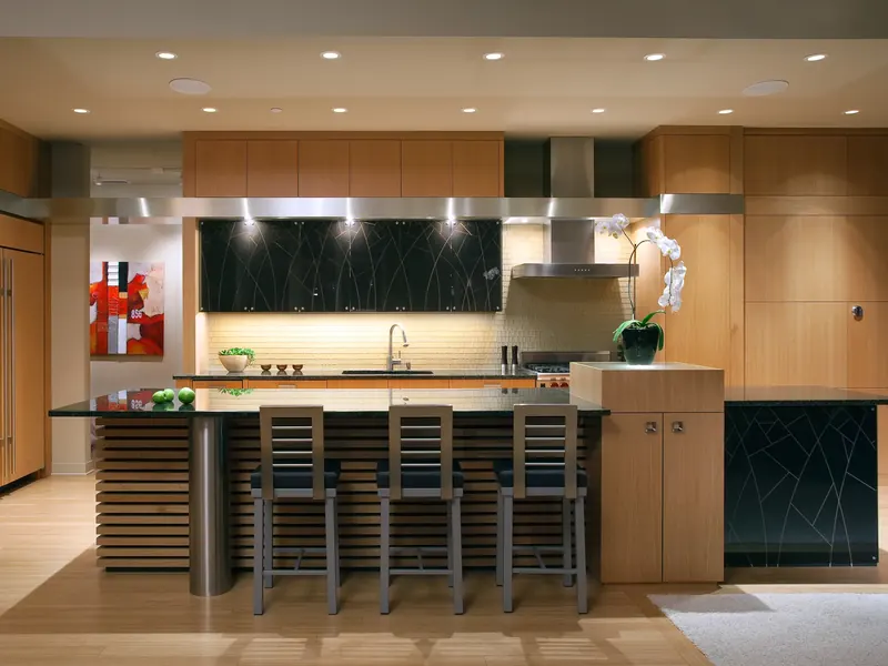 Loft kitchen island with horizontal wood slats, a black stone top and bar stools