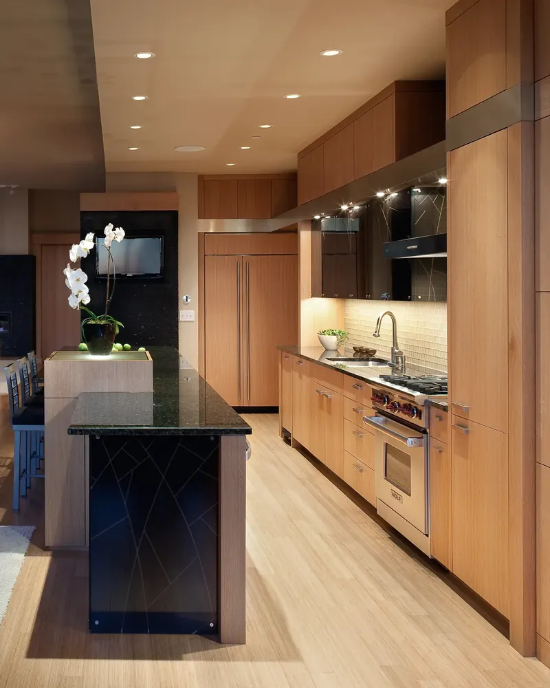 Galley view of the loft kitchen with an orchid on the lit island end