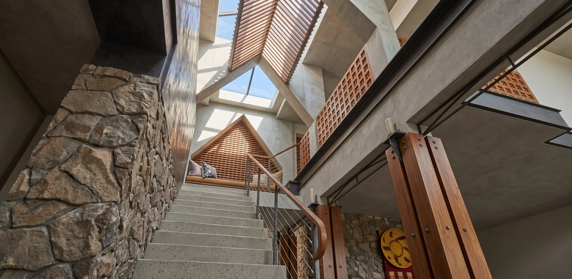 Looking up the stair to the peak skylight, filtered by a slatted wooden trellis above the window seat